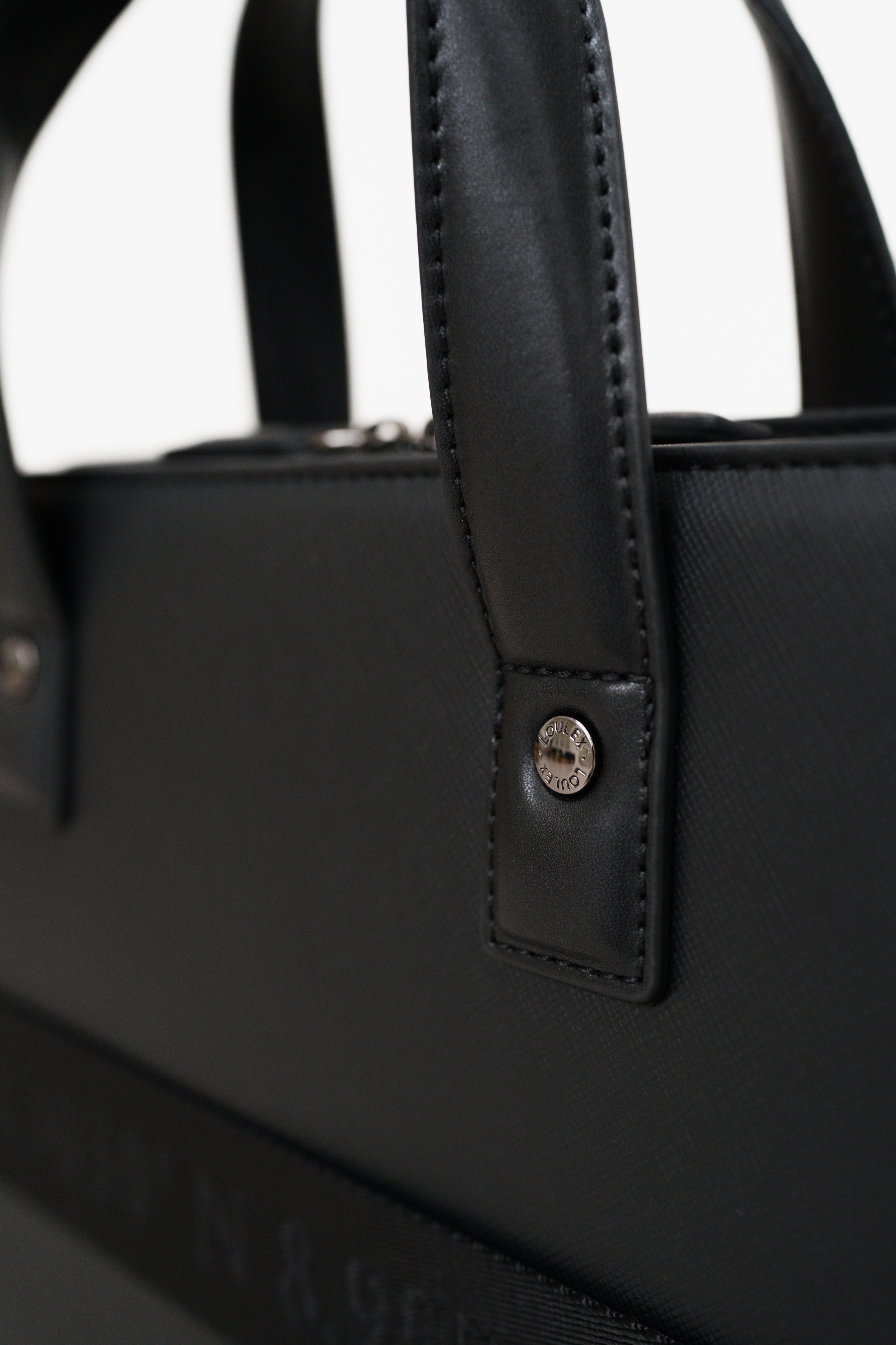 Close-up of a black handbag with a handle and metal clasp on a white background