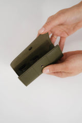 Mano sosteniendo una funda de teléfono verde sobre un fondo claro