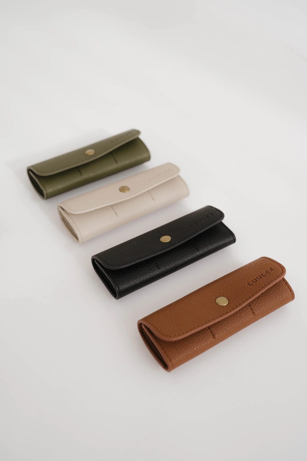 Four leather wallets in different colors on a light gray background