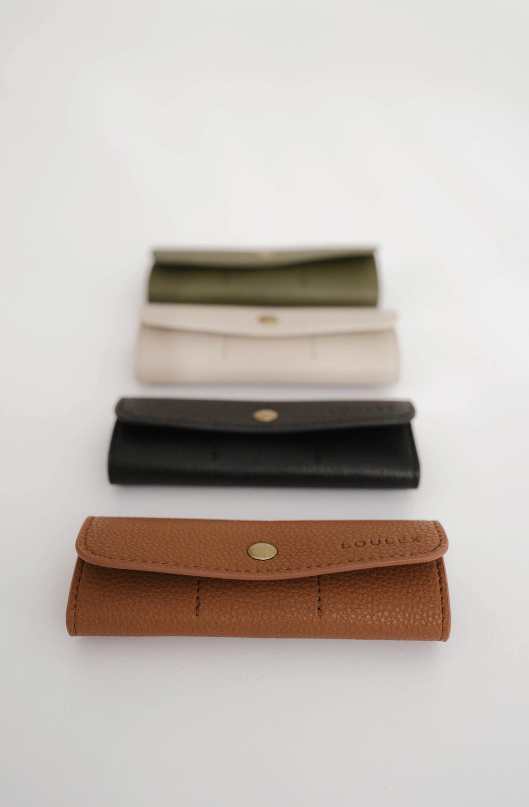 Three leather wallets in brown, black, and beige on a white background