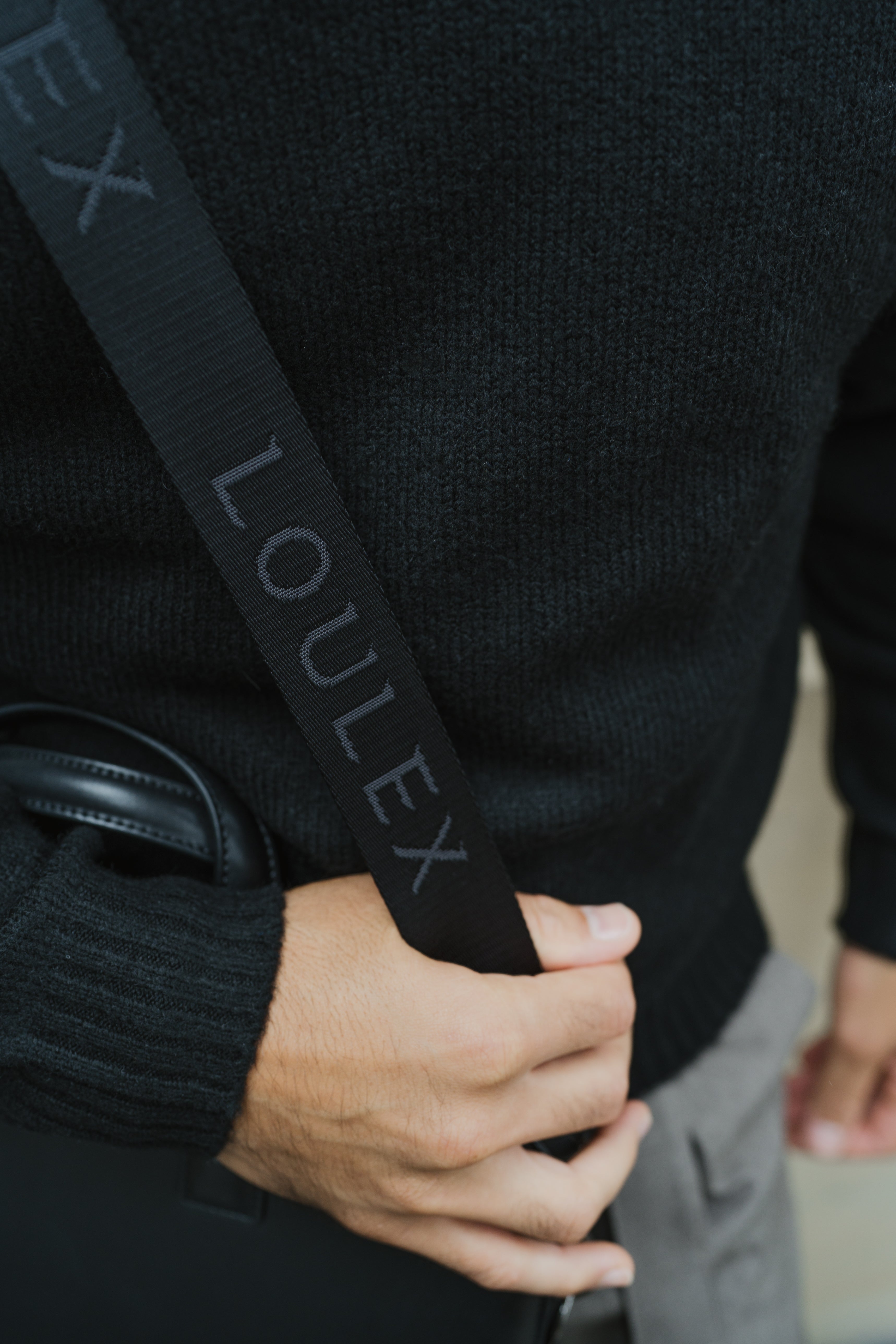 Person holding a black bag with 'LOULEX' branding.