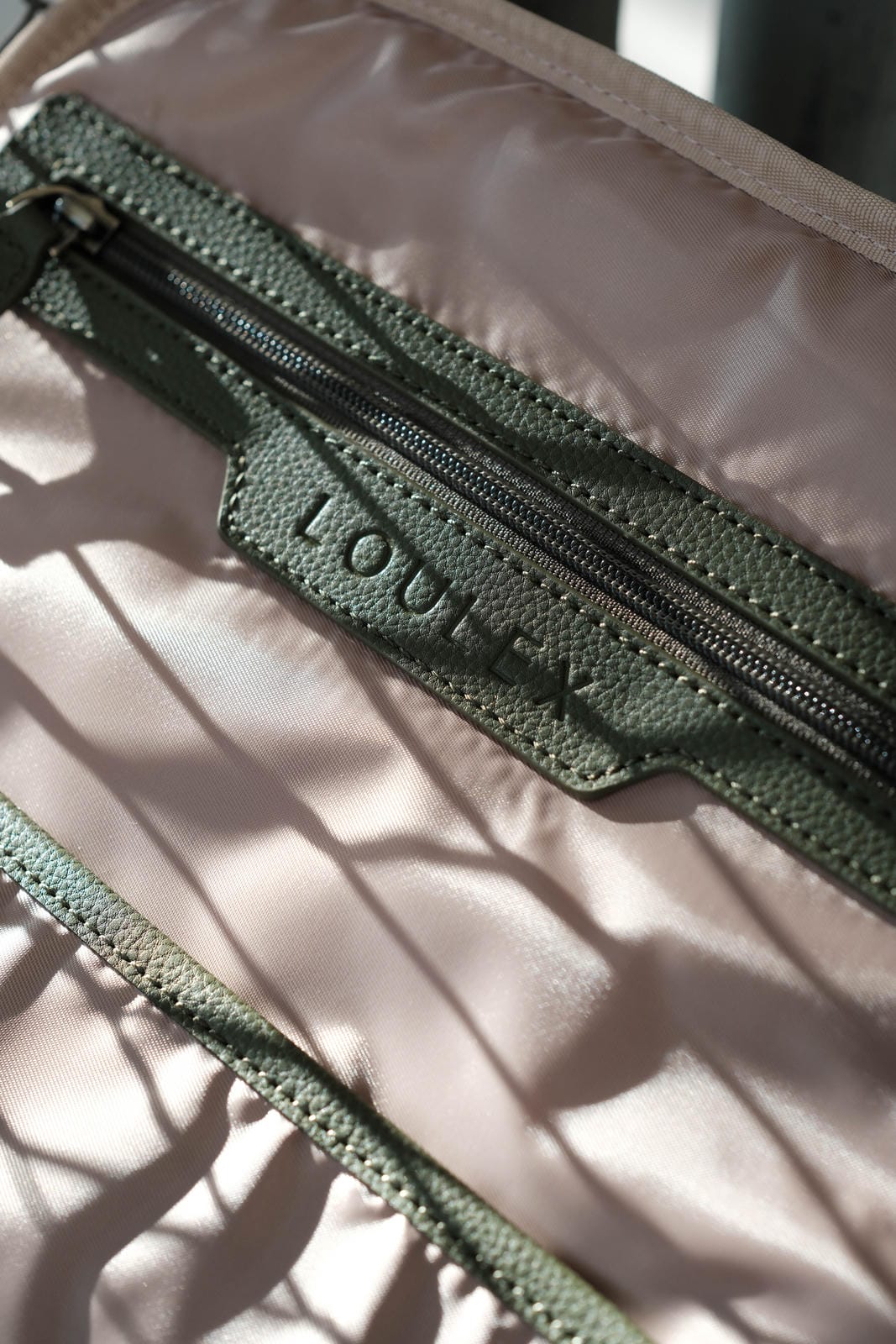 Green textured pouch with a zipper on a beige background