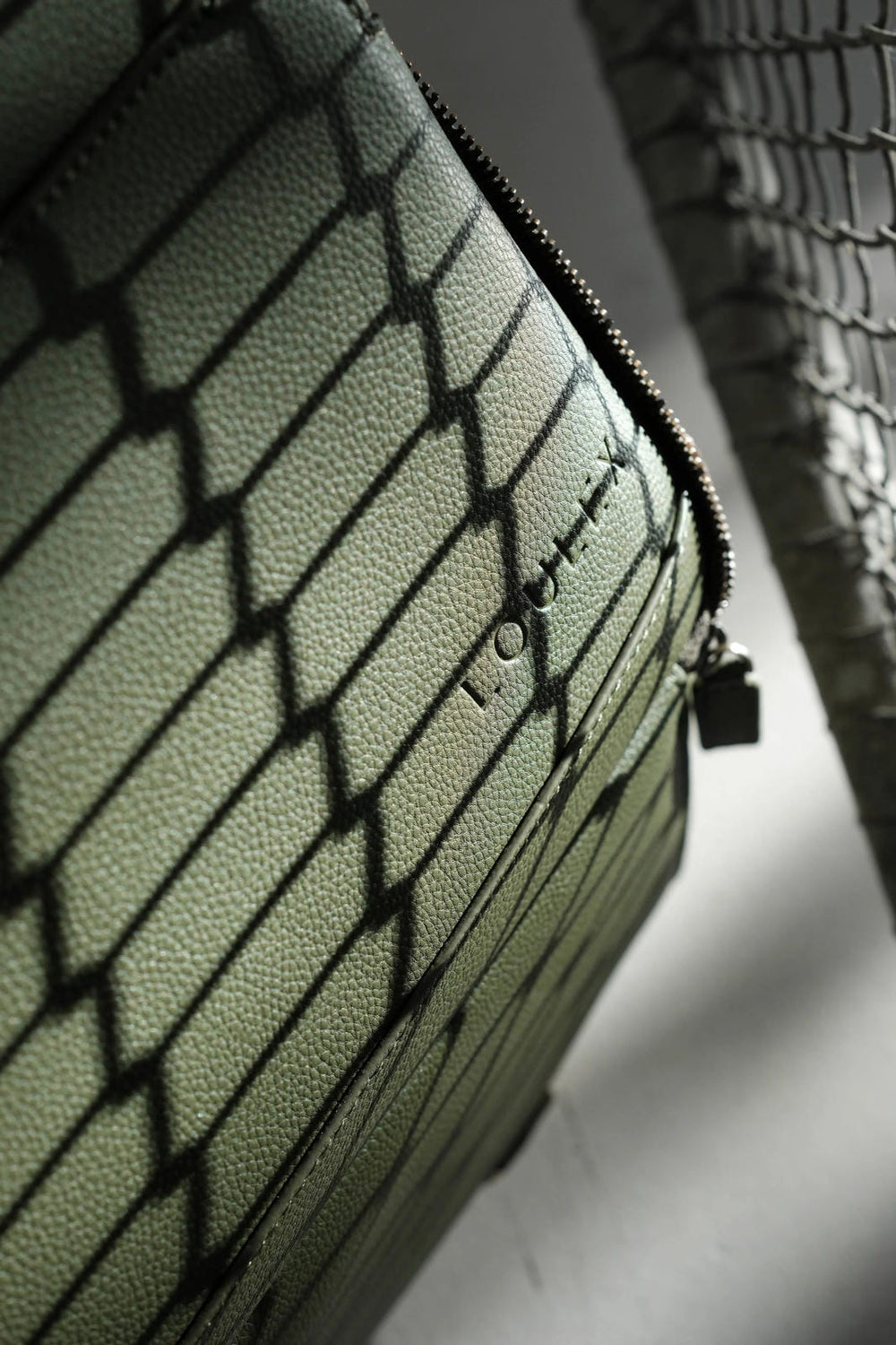 Borsa verde testurizzata con logo del marchio su sfondo neutro