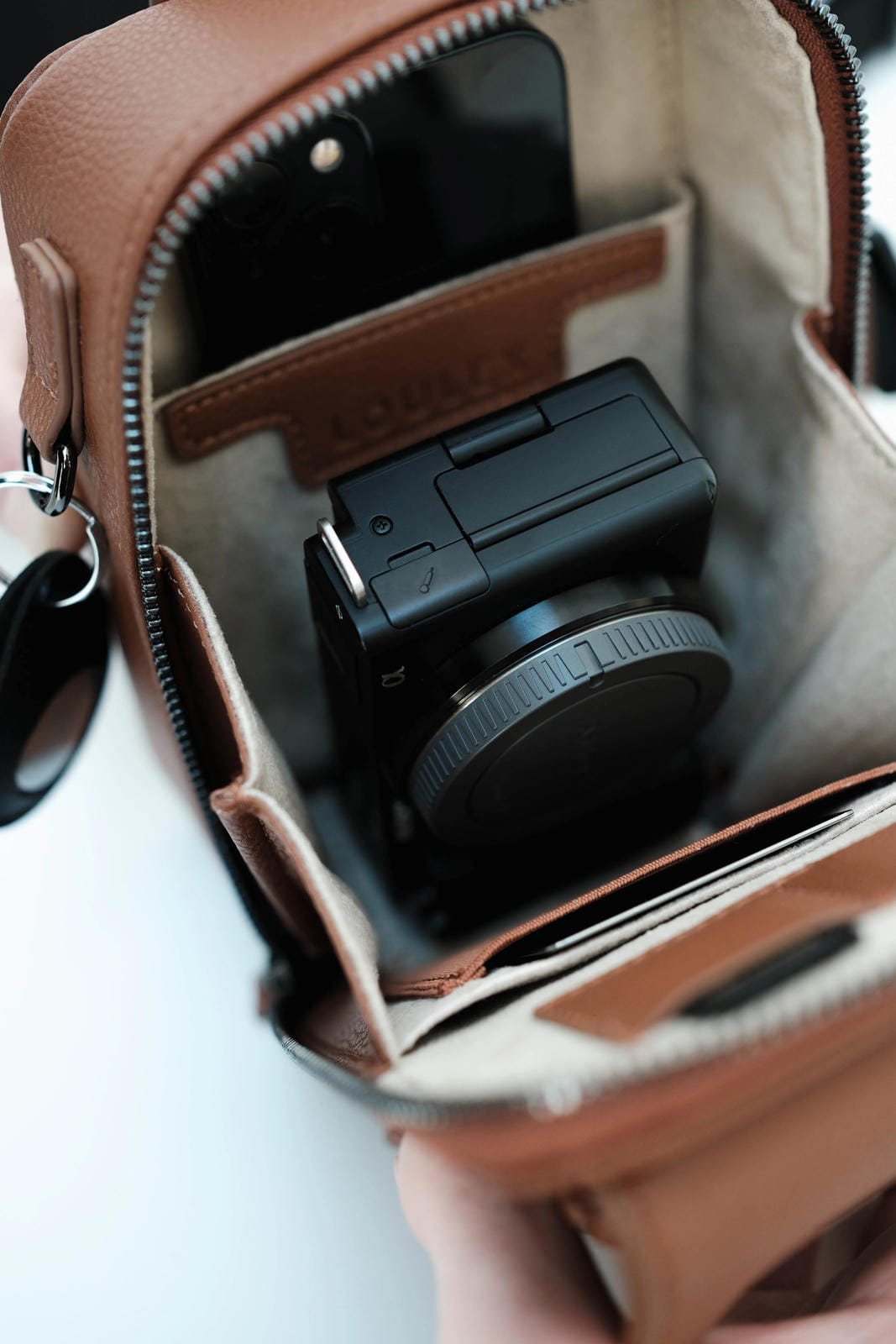 Camera lens and battery in a brown leather bag