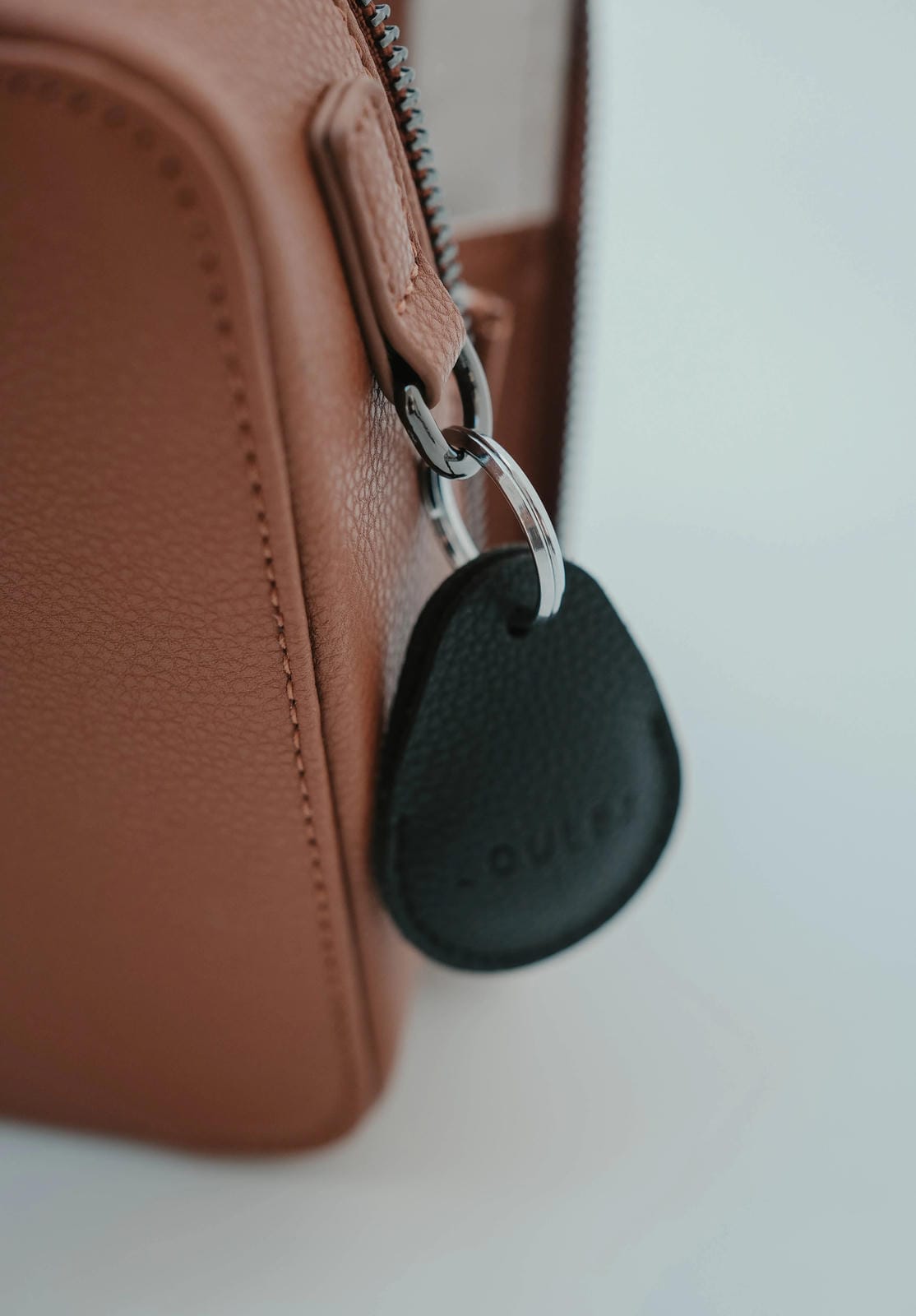 Black key tracker attached to a brown leather bag