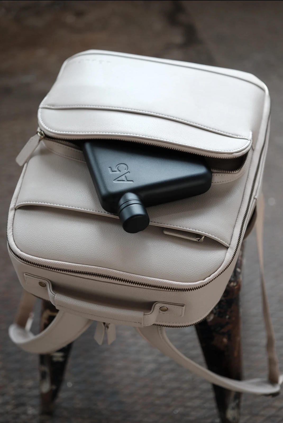 Beige backpack with a black air blower on a textured surface