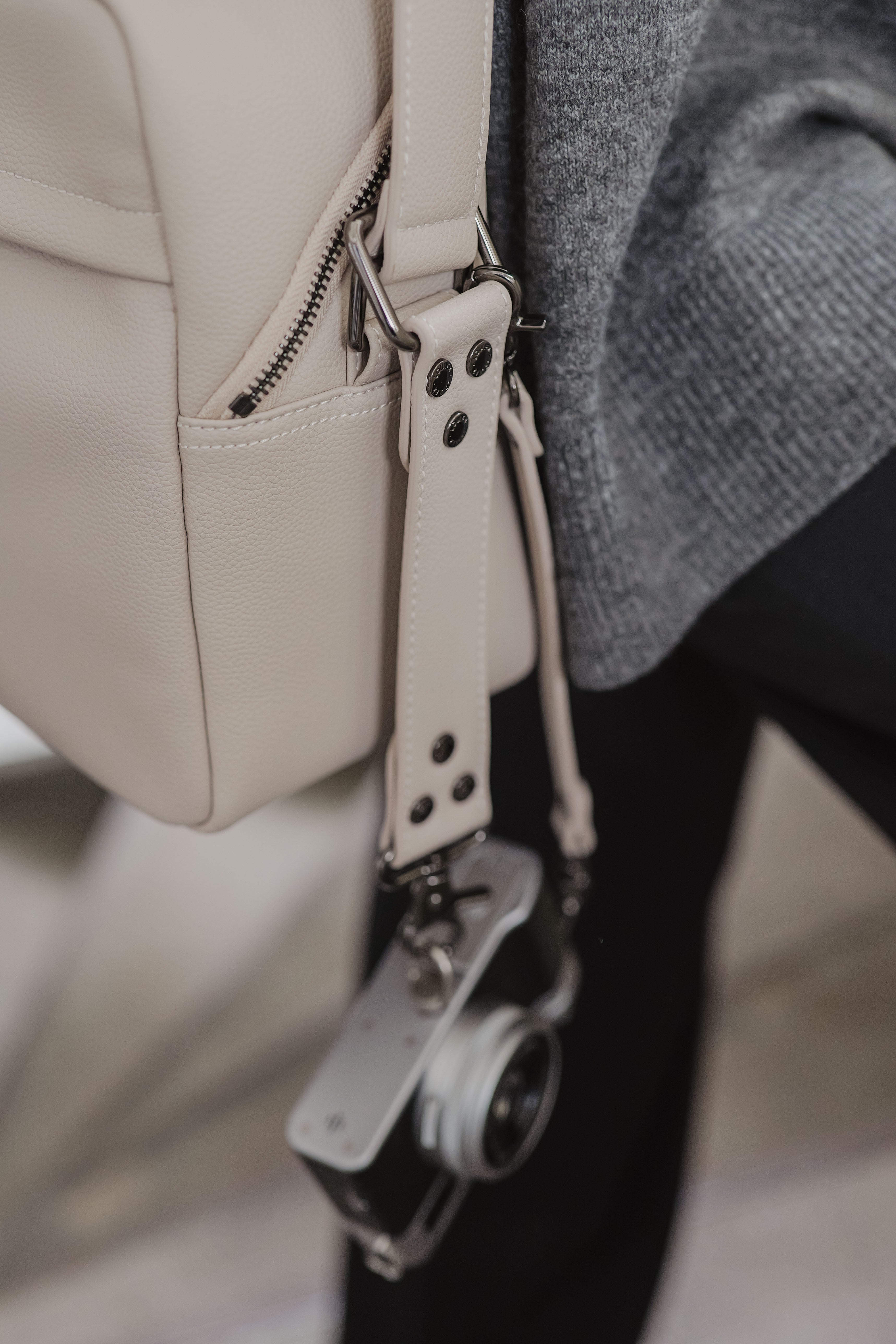 Close-up van een beige leren tas met een camera aan de riem.
