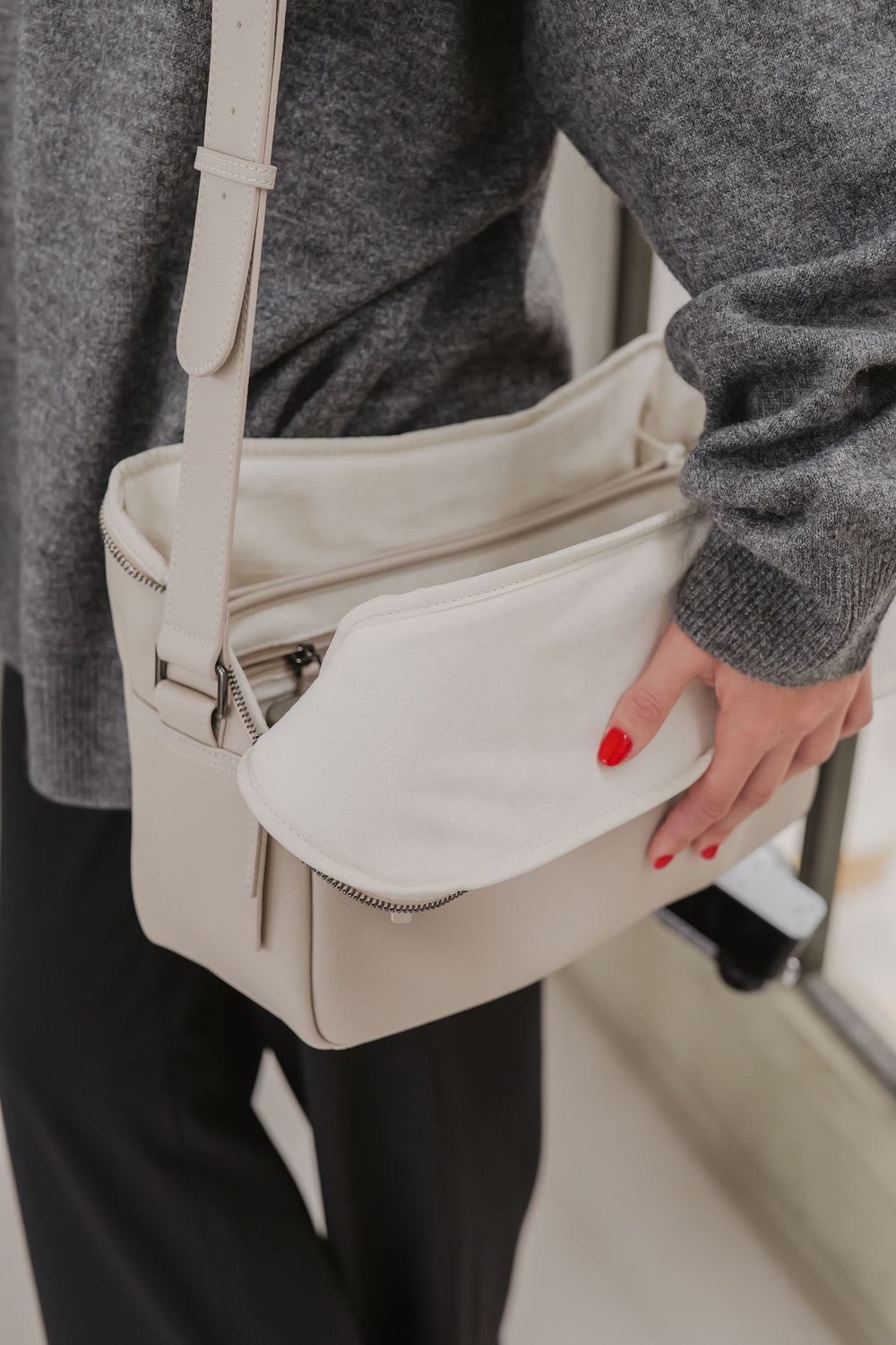 Osoba trzymająca beżową torebkę na rozmyłym tle