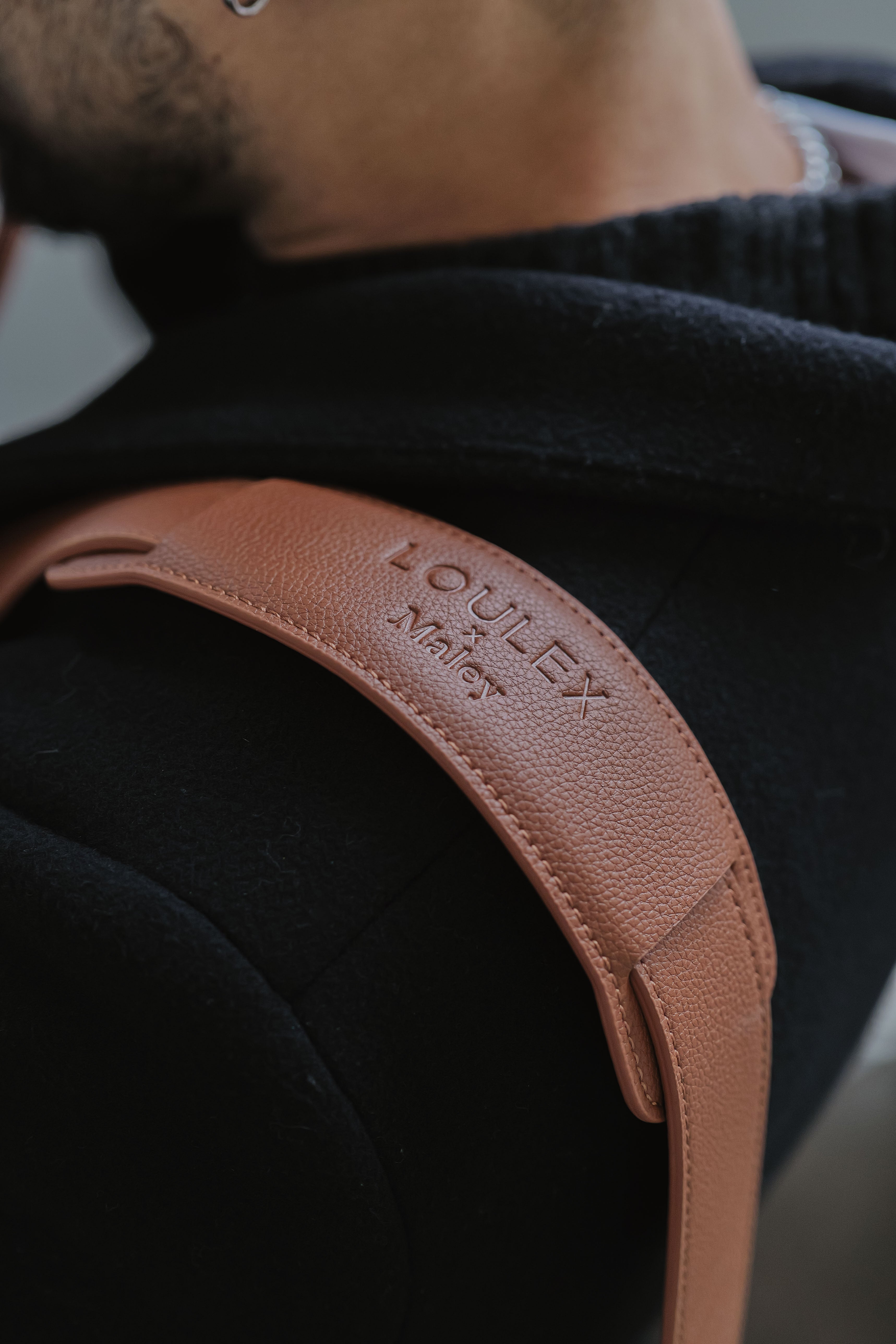 Bruine leren riem met 'LOWLEY'-logo op een donkere achtergrond