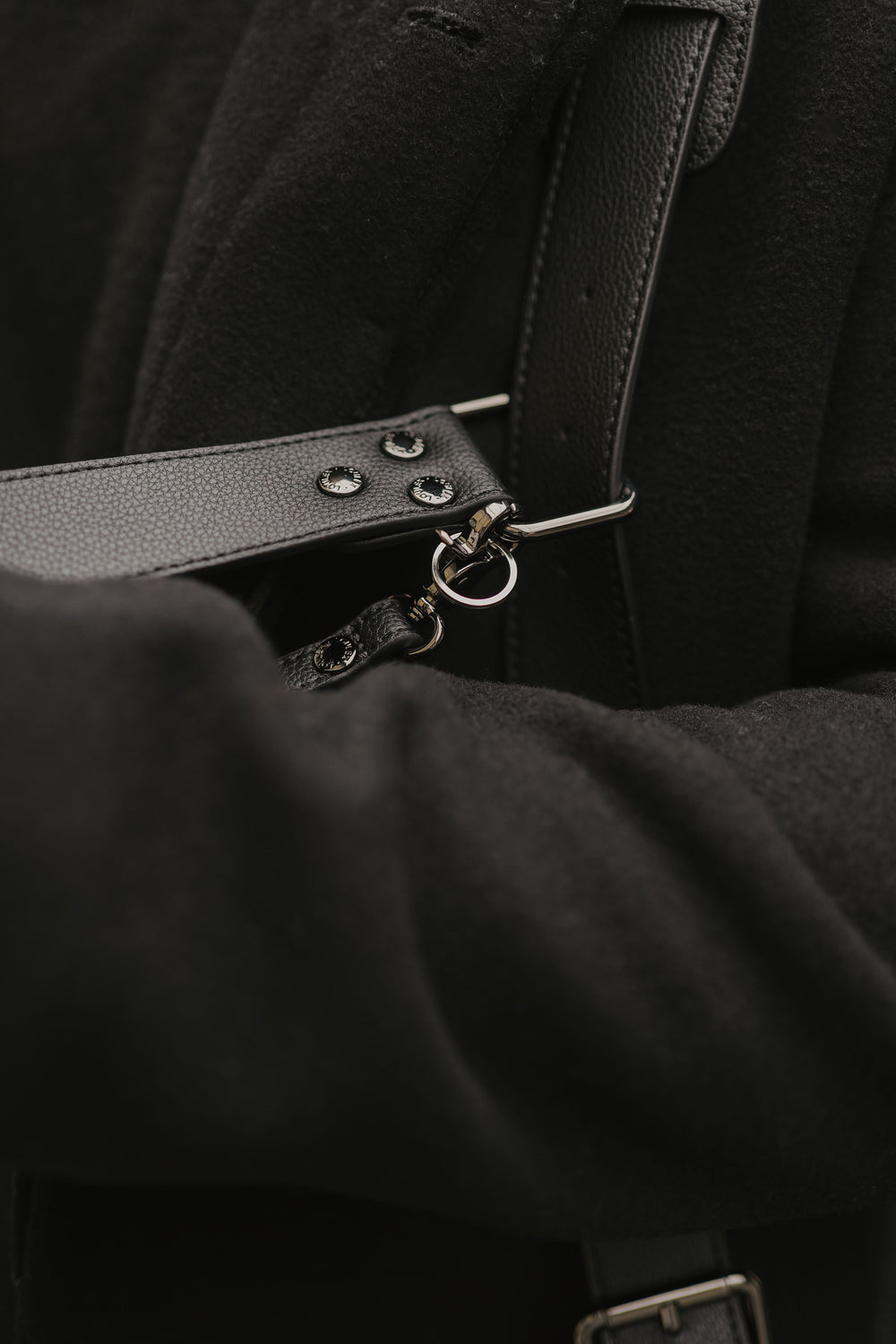 Zbliżenie na czarny skórzany pasek z metalowymi okuciami na ciemnym tle