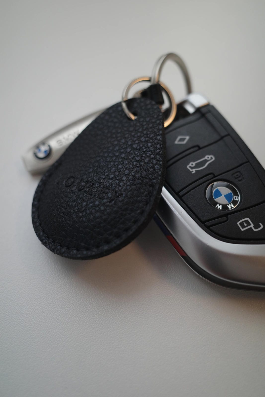 Car key with black keychain on a light gray surface