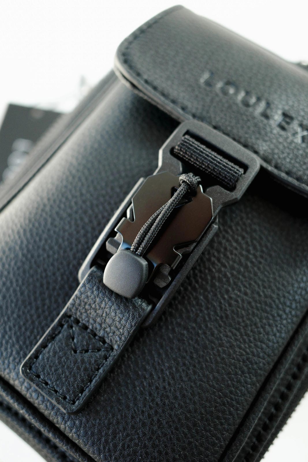 Close-up of a black leather wallet with a zipper detail, featuring the brand 'Louis Vuitton'.