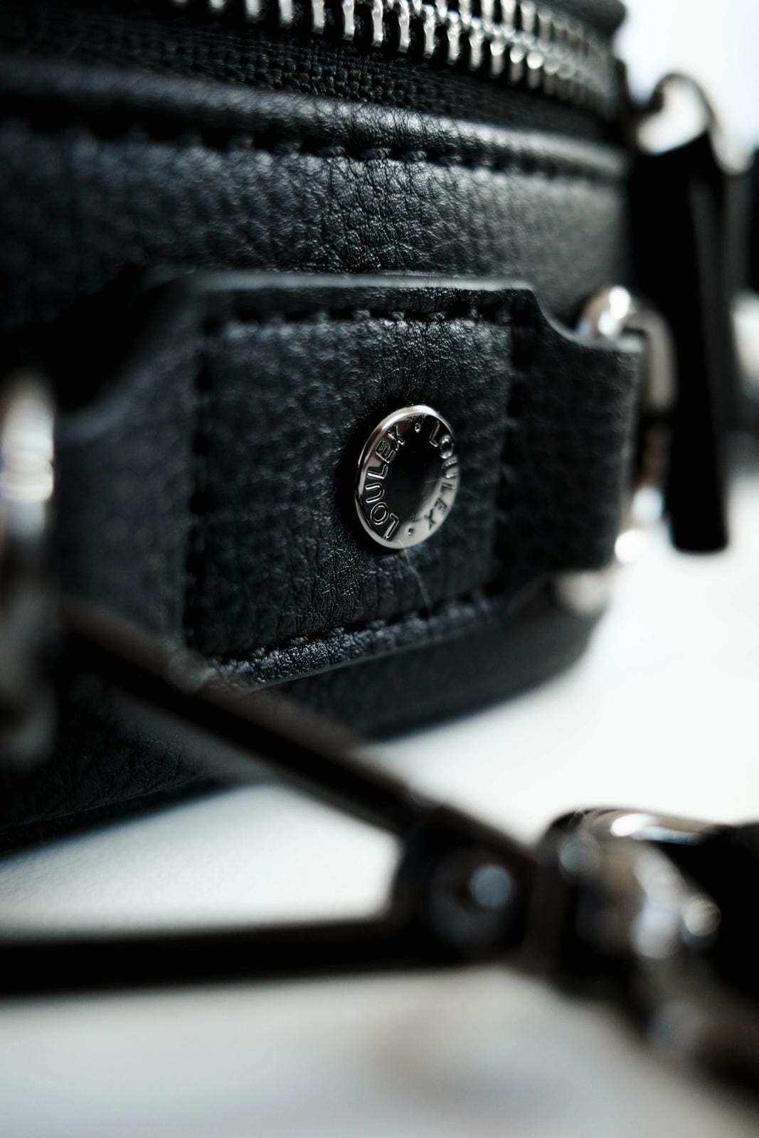 Close-up of a black textured bag with a metal clasp on a blurred background