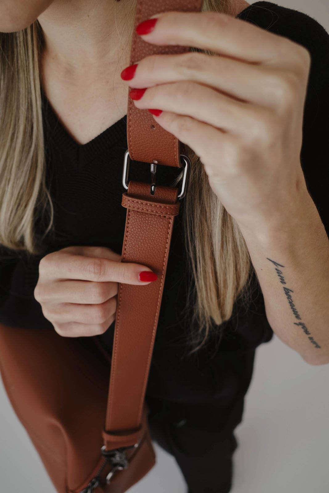 Person holding a brown leather strap with a buckle