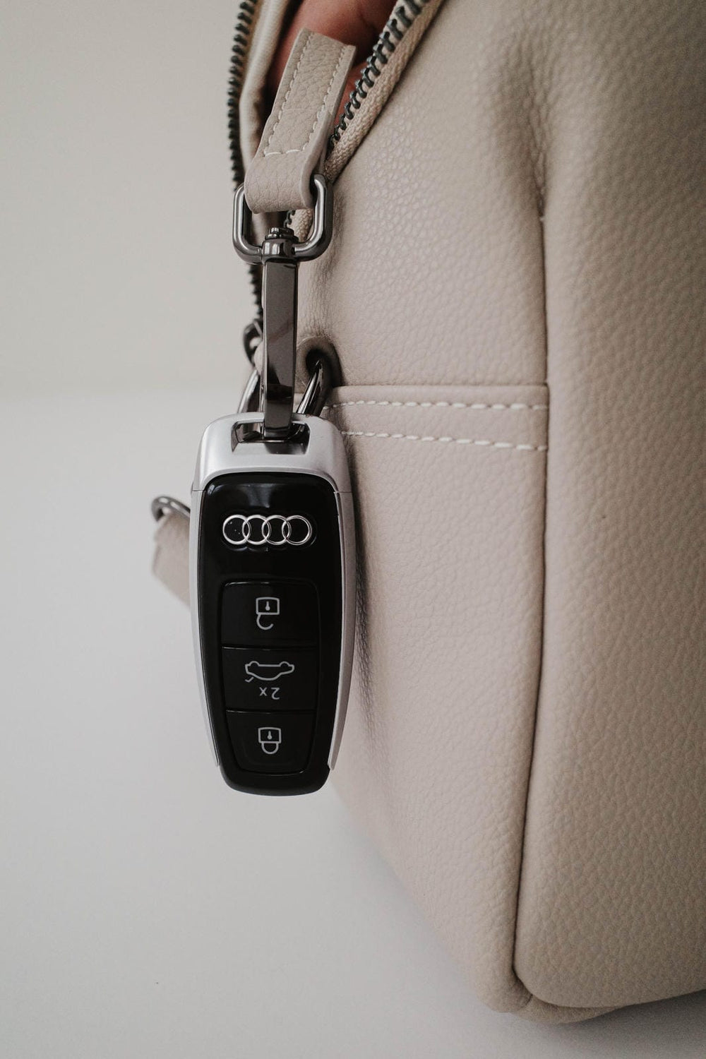 Llavero Audi adherido a un bolso beige