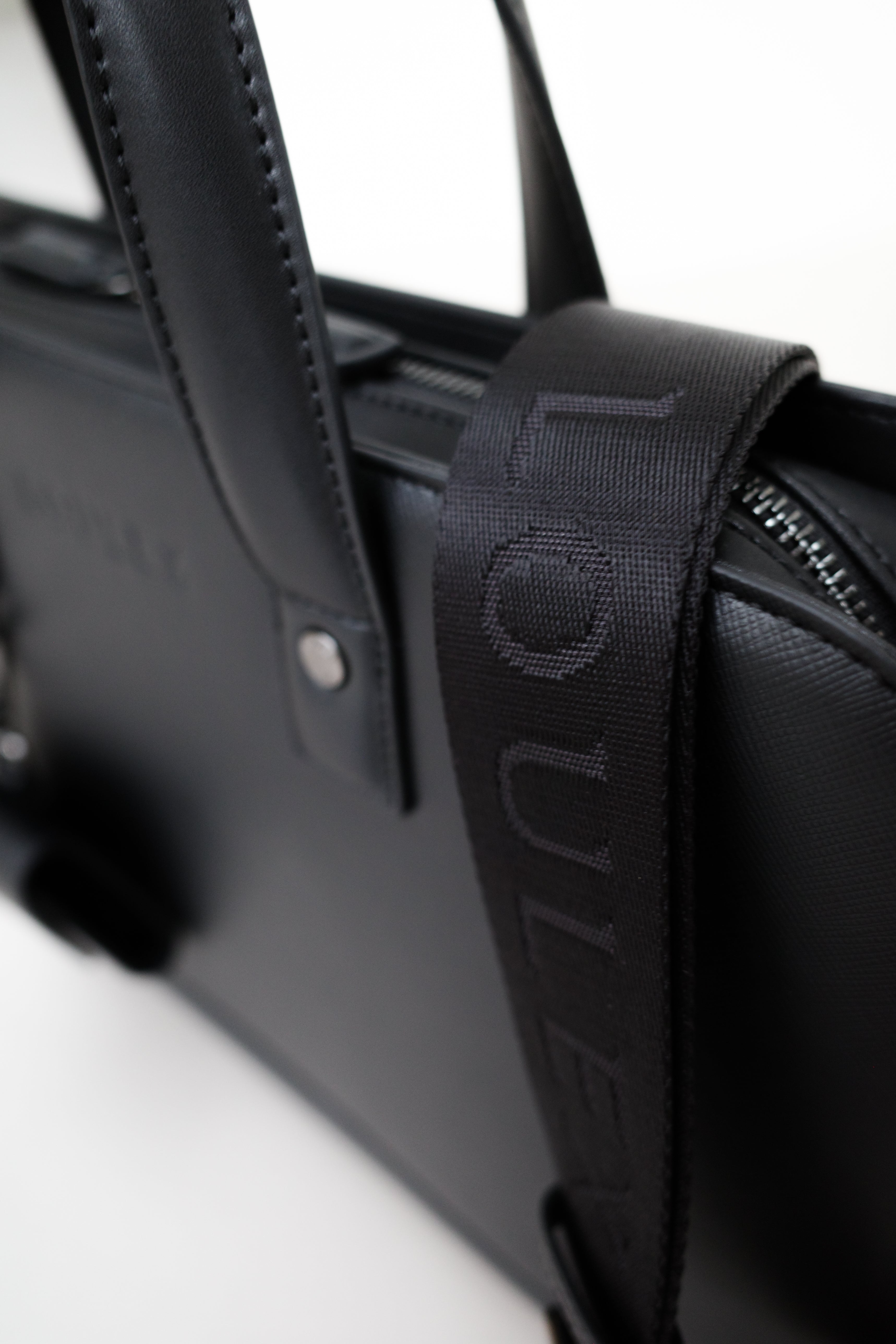 Black leather bag with a strap featuring a brand logo on a white background