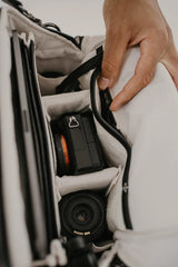 Attrezzatura fotografica all'interno di una borsa con una mano che regola la tracolla.