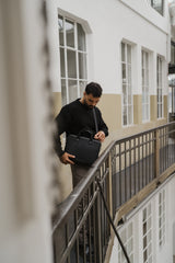 Uomo con una borsa nera su un balcone con un edificio sullo sfondo