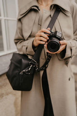Persona con una macchina fotografica e una borsa nera a tracolla