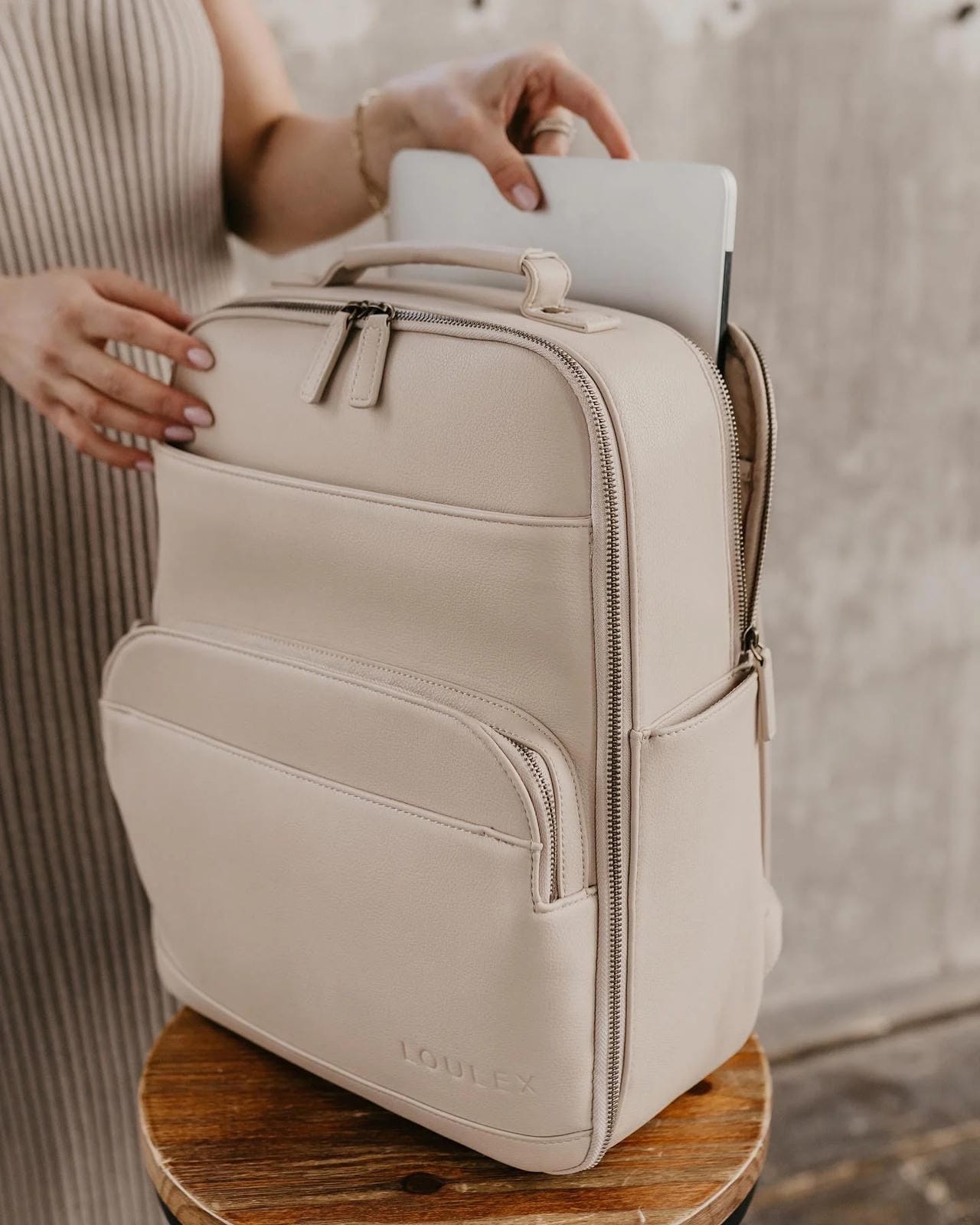 Beige backpack with a laptop on a wooden surface
