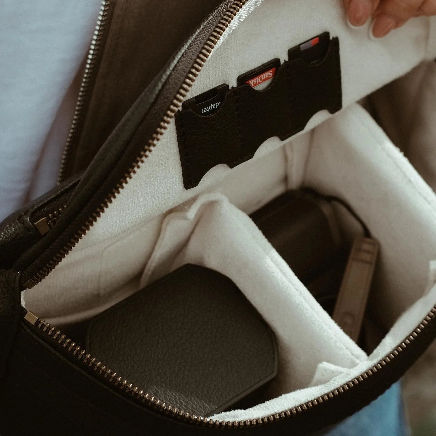 Interior view of a loulex professional camera bag featuring plush protective lining, padded dividers, and dedicated leather slots for SD card storage.
