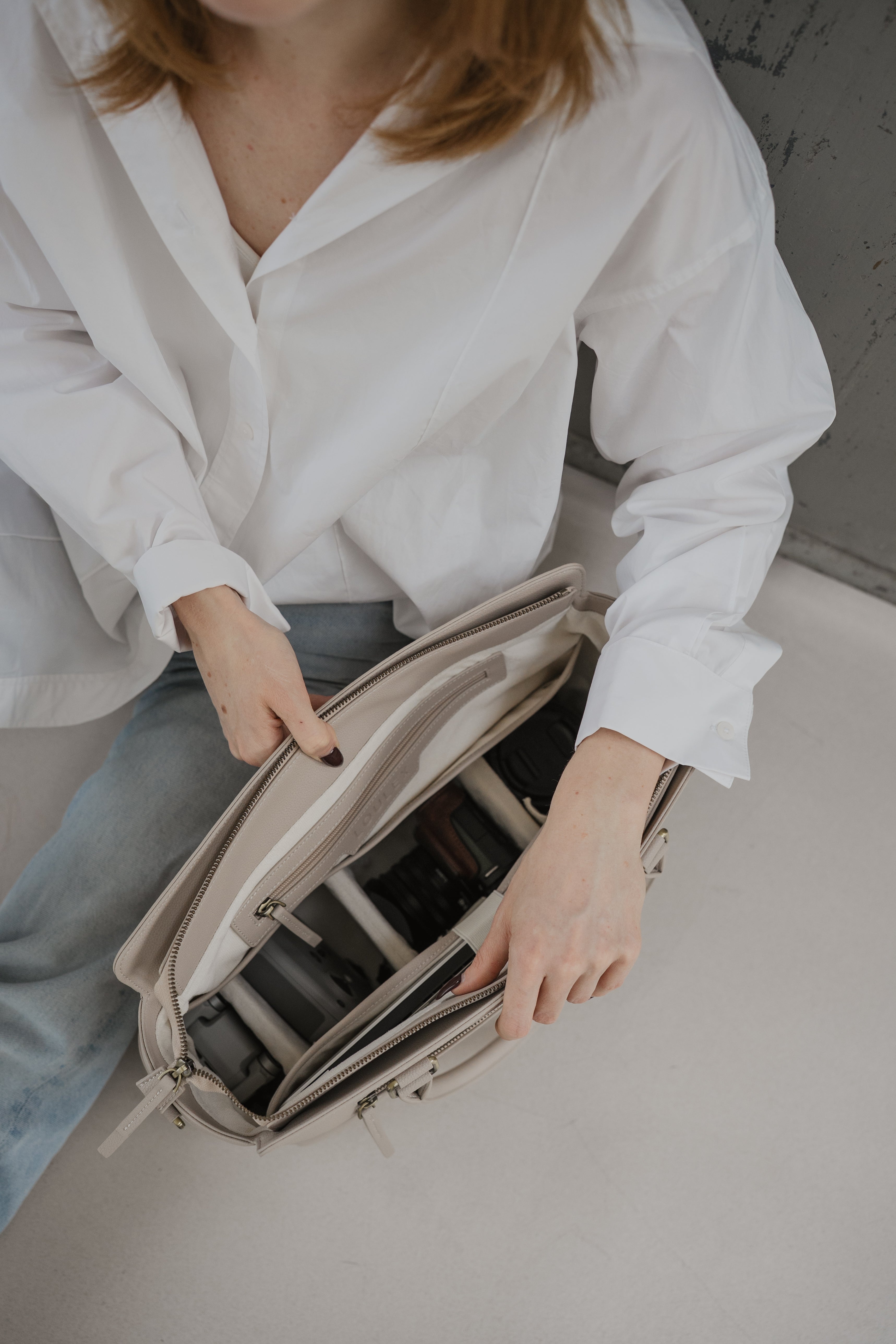 Personne ouvrant un sac de voyage beige sur une surface claire