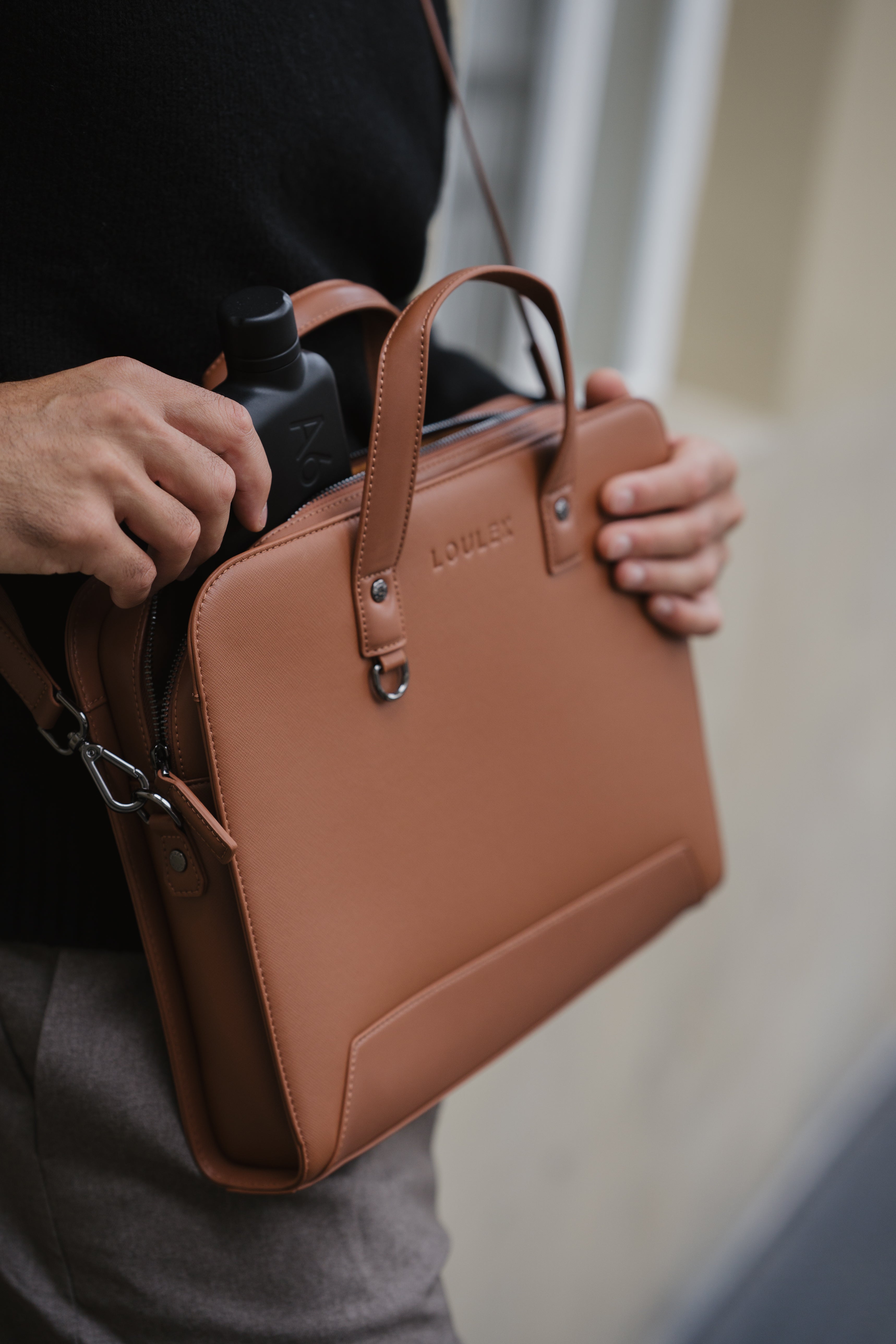 Brown leather briefcase held by a person with a blurred background