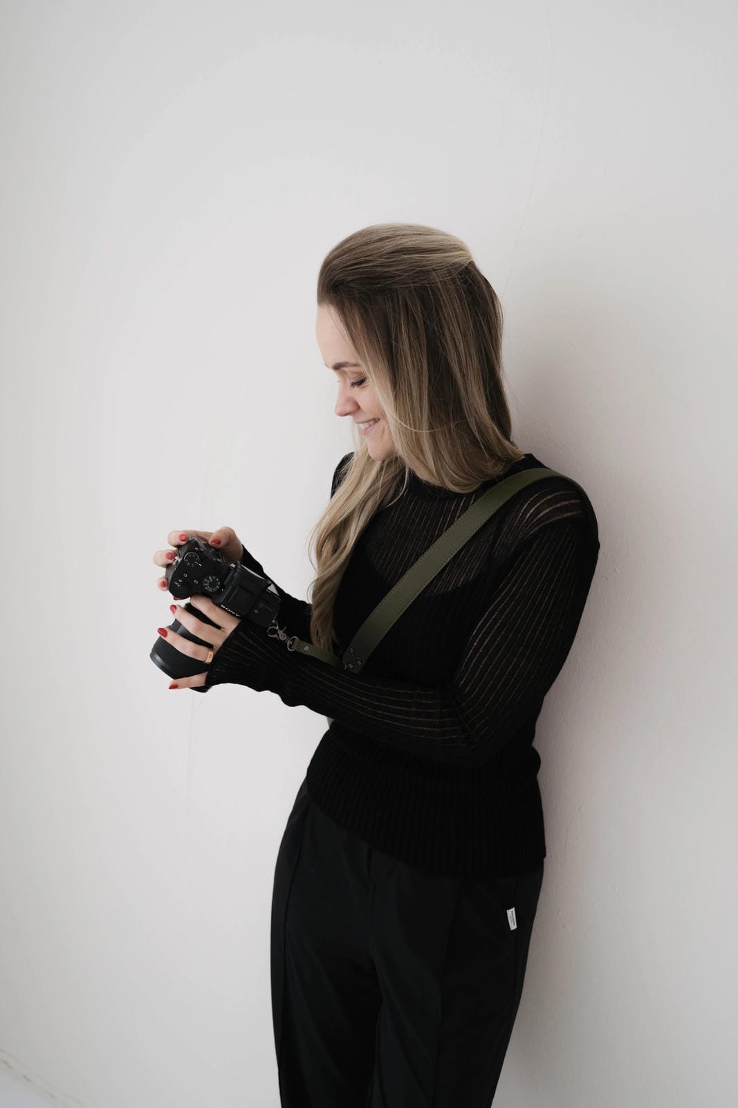 Person holding a camera against a white wall