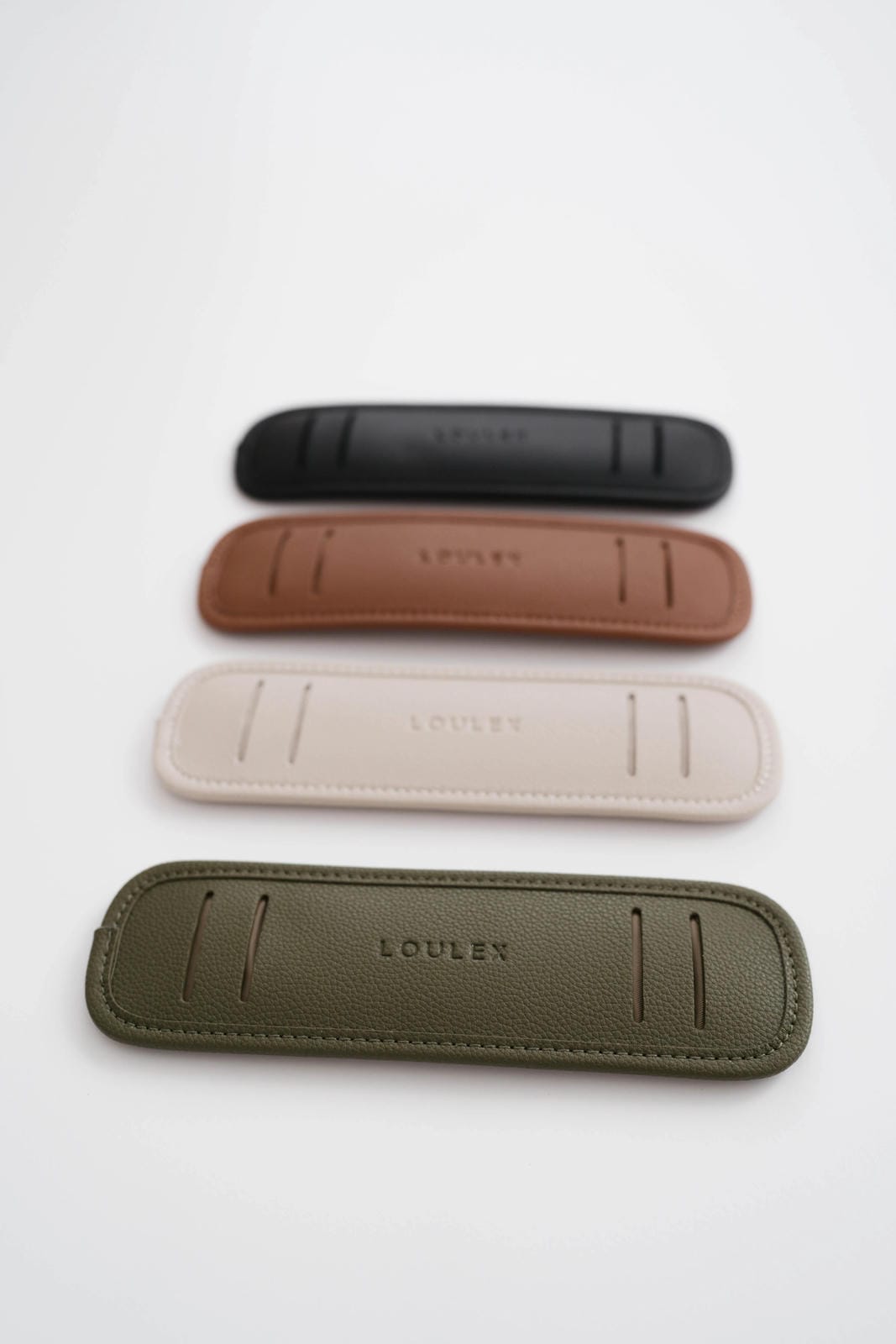Five leather pouches in different colors on a white background