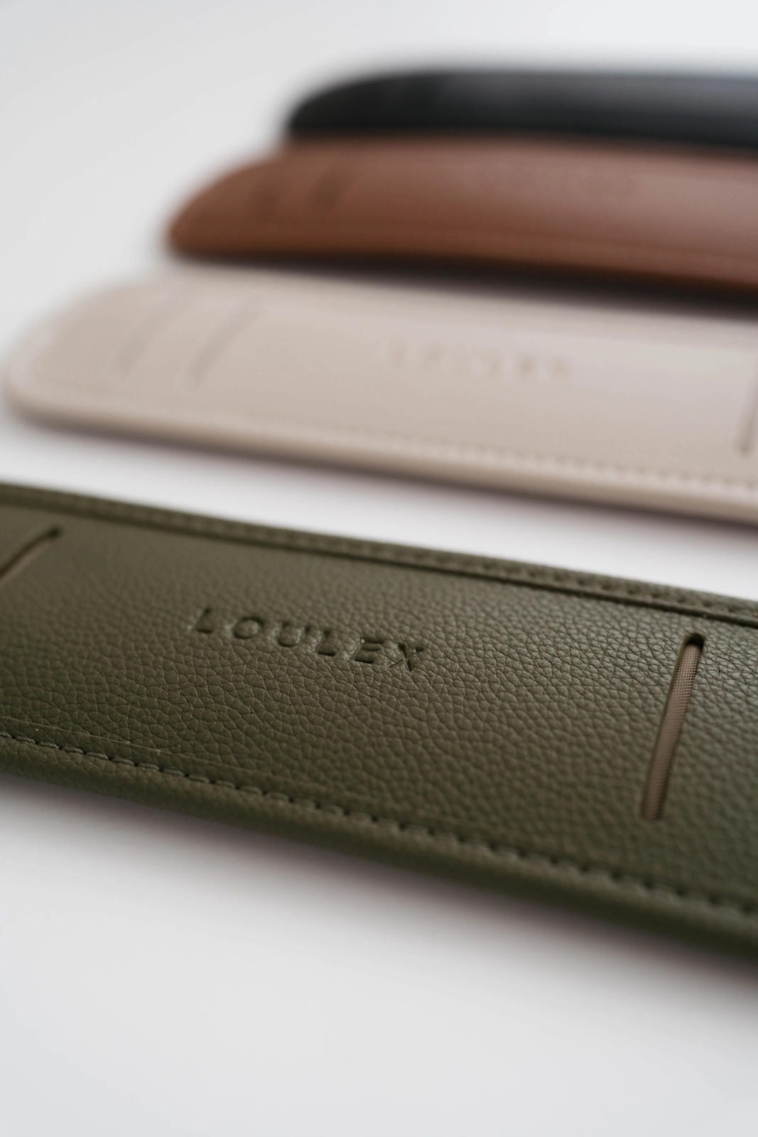 Three leather phone cases in green, brown, and beige with 'LOULEX' branding on a light background.