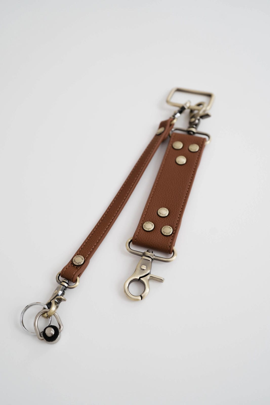 Brown leather strap with metal hardware on a white background