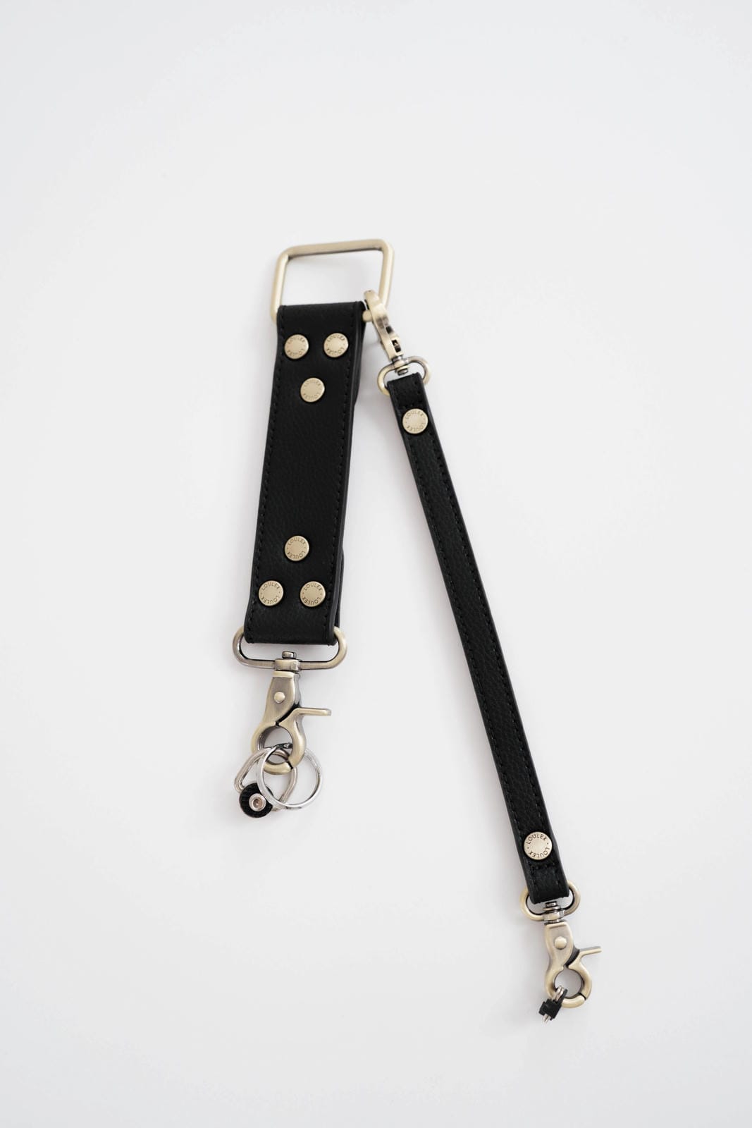Black leather studded strap with silver hardware on a white background