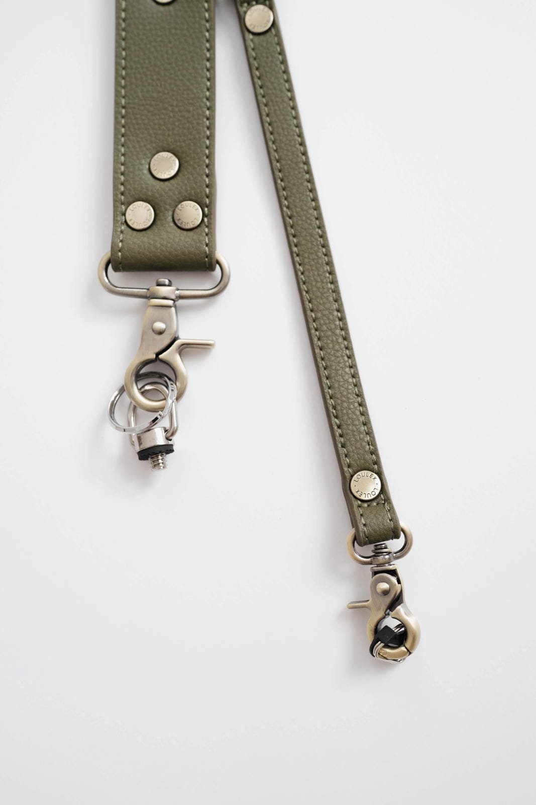 Green leather strap with metal hardware on a white background