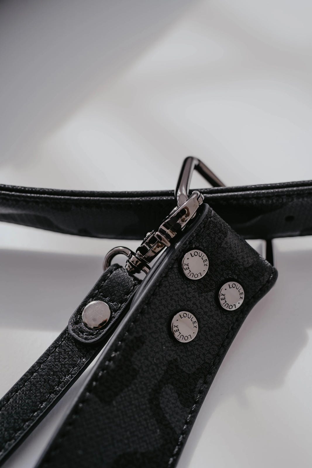 Black leather strap with silver hardware on a white background