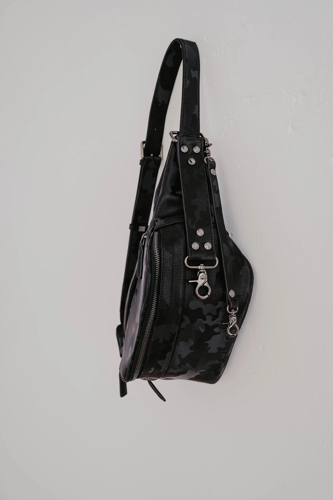 Black leather backpack with studded details on a light gray background