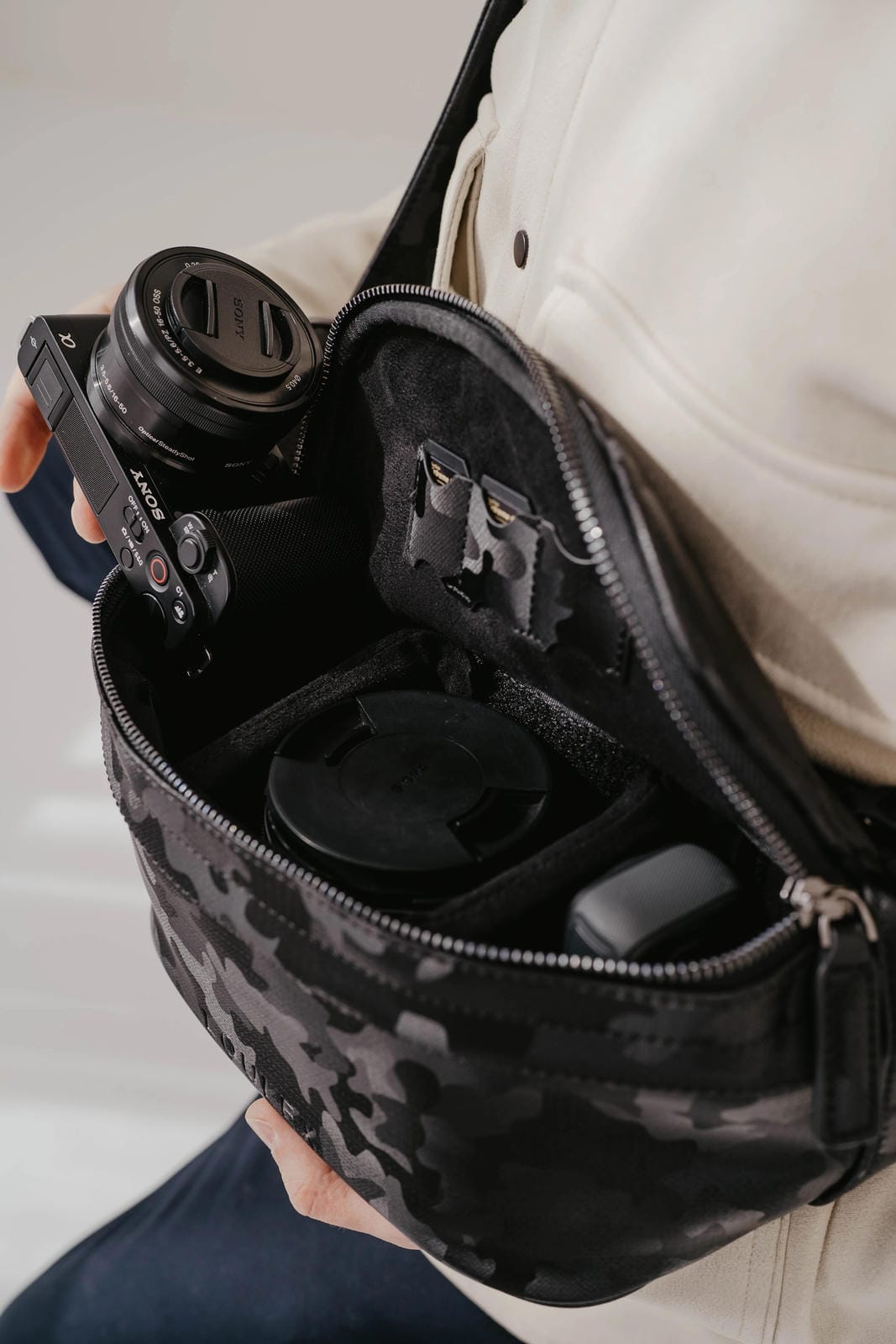 Person holding a camera and a floral-patterned bag with compartments.