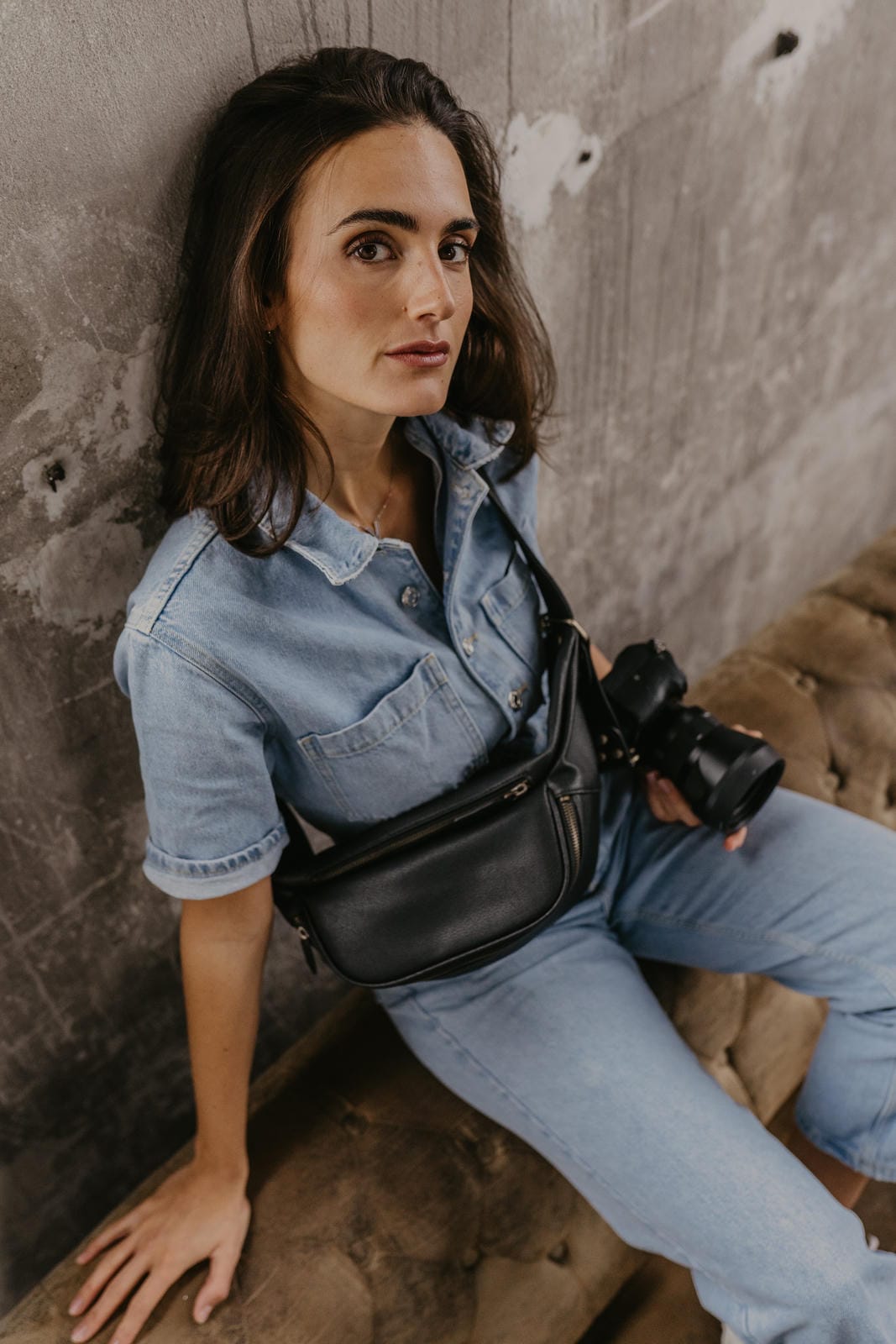 Woman holding a camera against a textured wall
