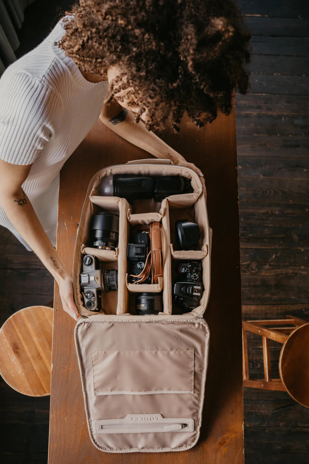 A couple showcasing loulex leather bags, featuring a cream leather tote and a tan messenger camera bag in an urban street-style setting.