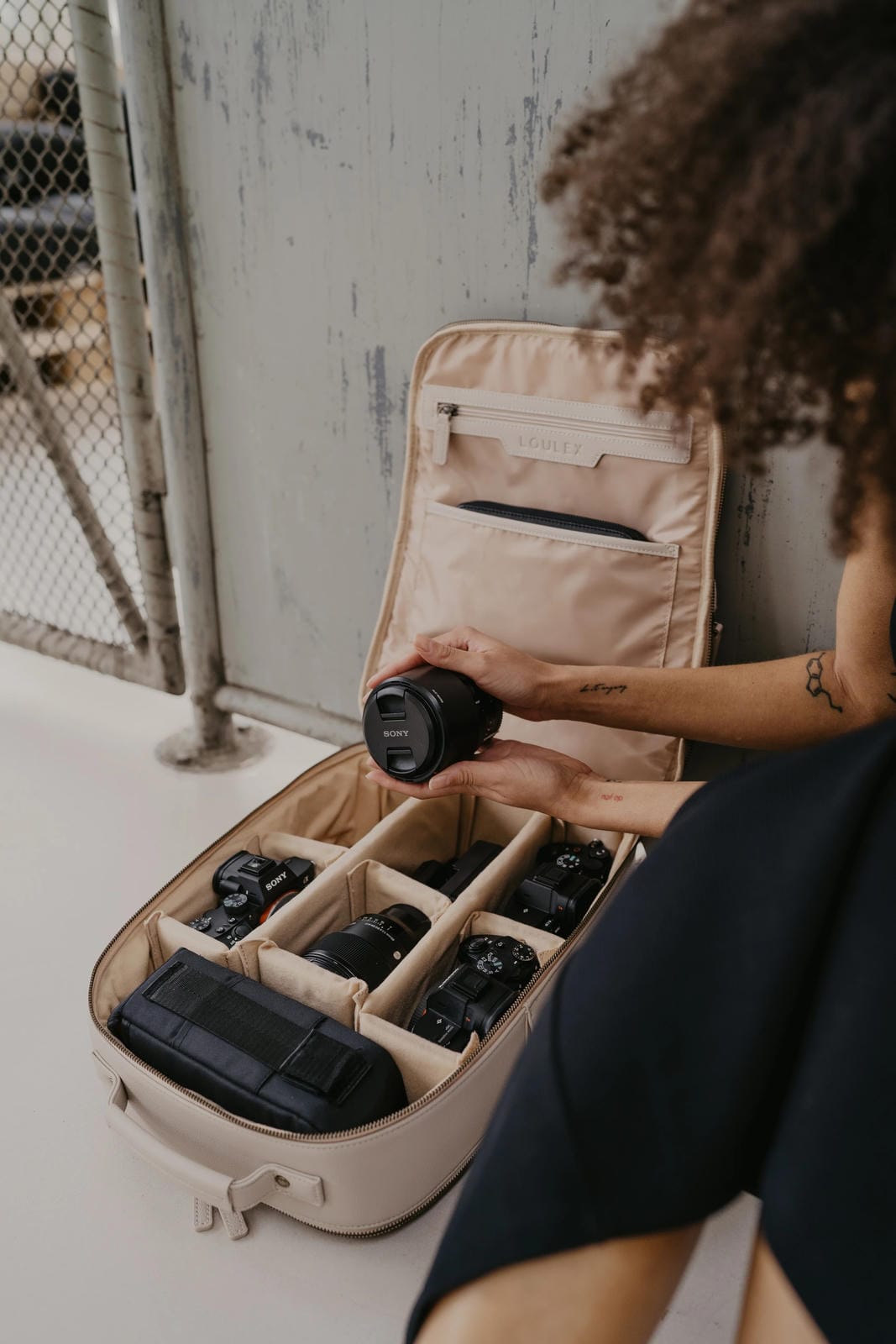 Person organizing camera equipment in a beige travel case.