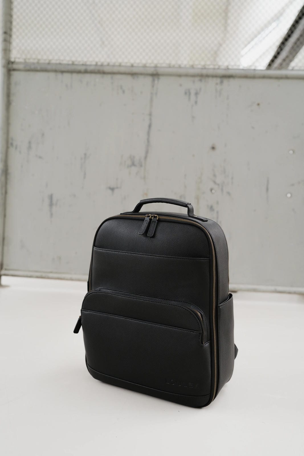 Black backpack on a white surface with a light gray background