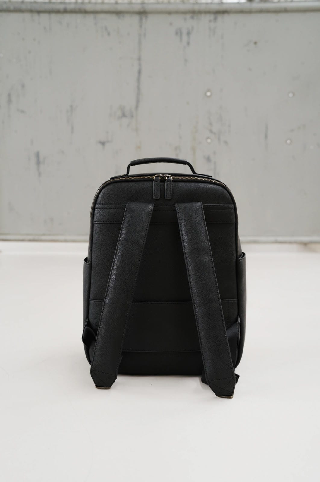 Black backpack on a white surface with a light gray background