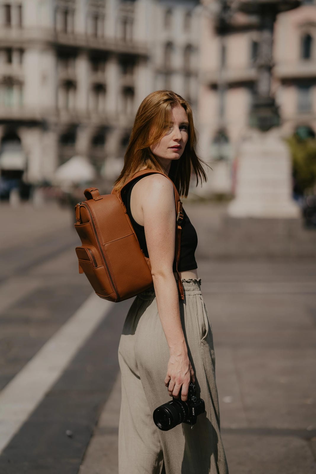 Woman with a brown backpack and camera in an urban setting