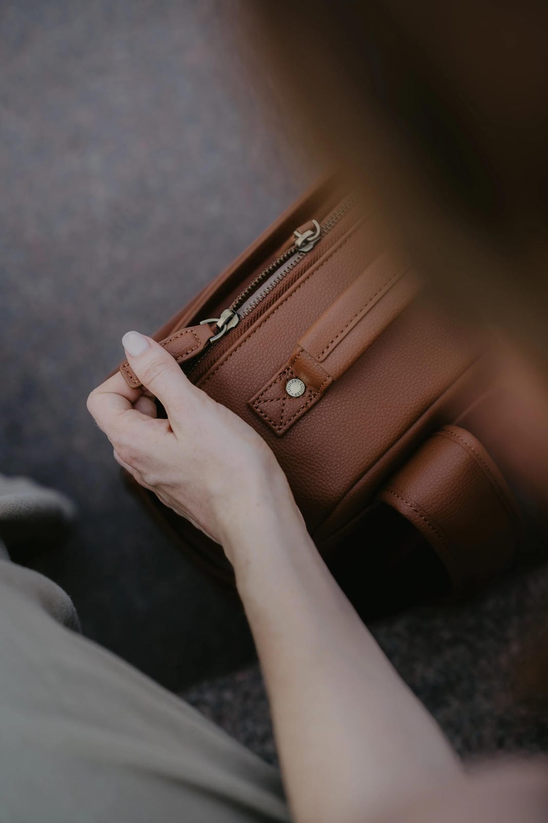 Hand opening a brown leather wallet on a blurred background