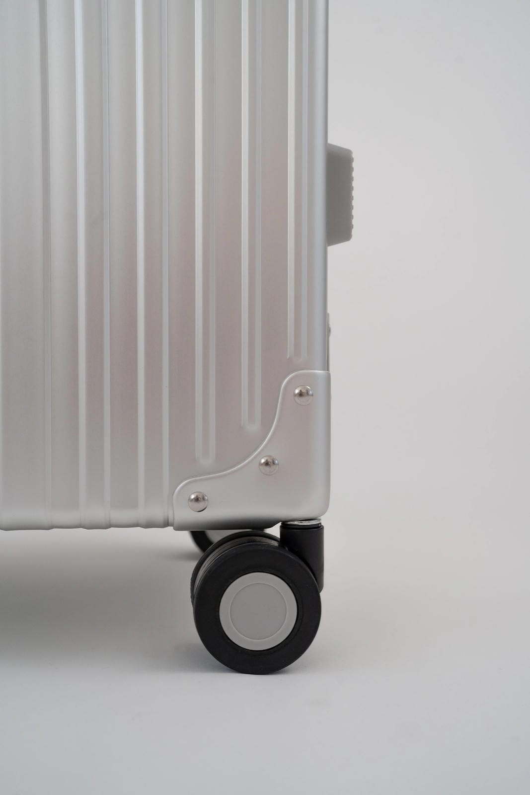 Close-up of a silver suitcase with a wheel on a light gray background