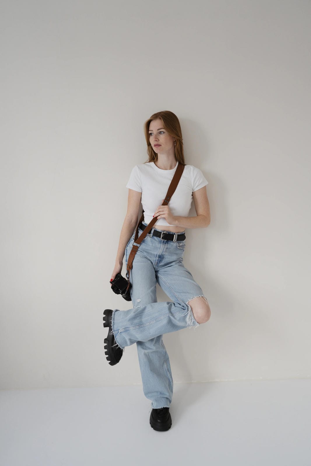 Woman in white t-shirt and light blue jeans posing against a plain background