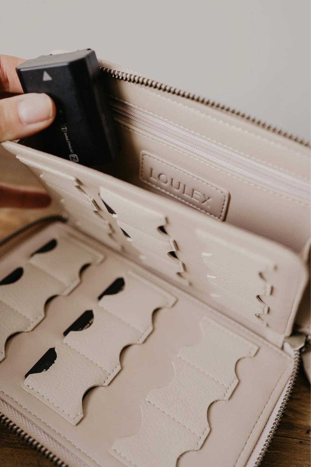 Beige wallet with cut-out design held open by a hand, featuring the brand 'Louielex'.