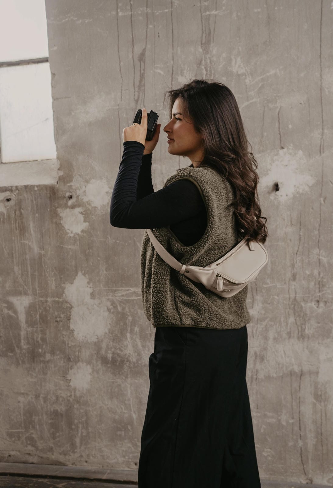 Woman holding a camera against a textured wall