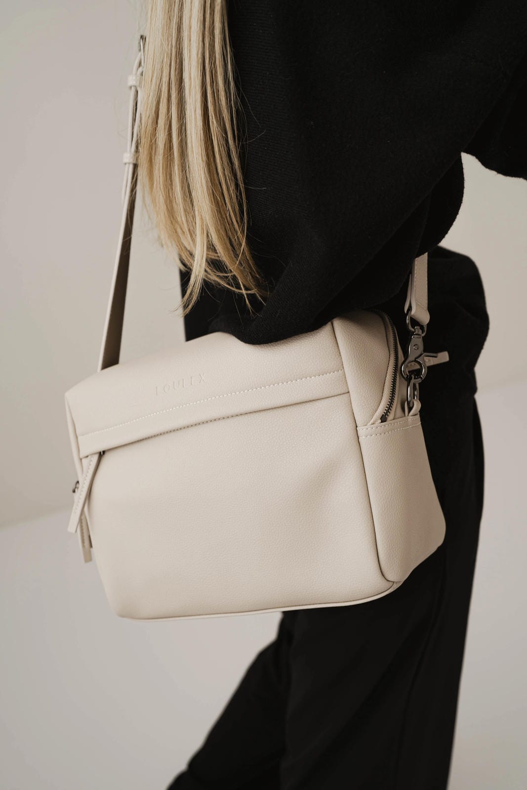 Beige handbag worn over the shoulder against a neutral background