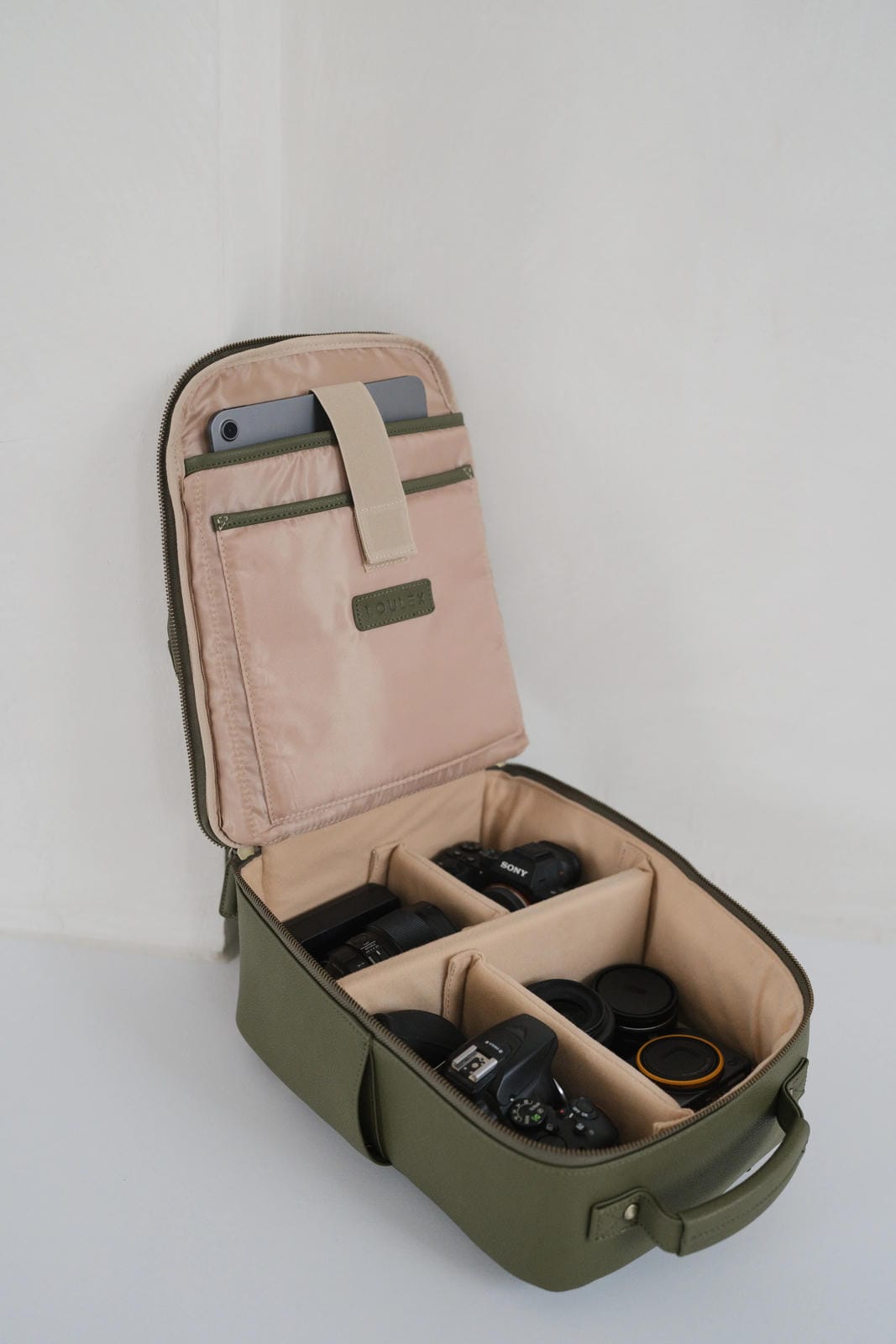 Green travel case with compartments for camera equipment on a white background