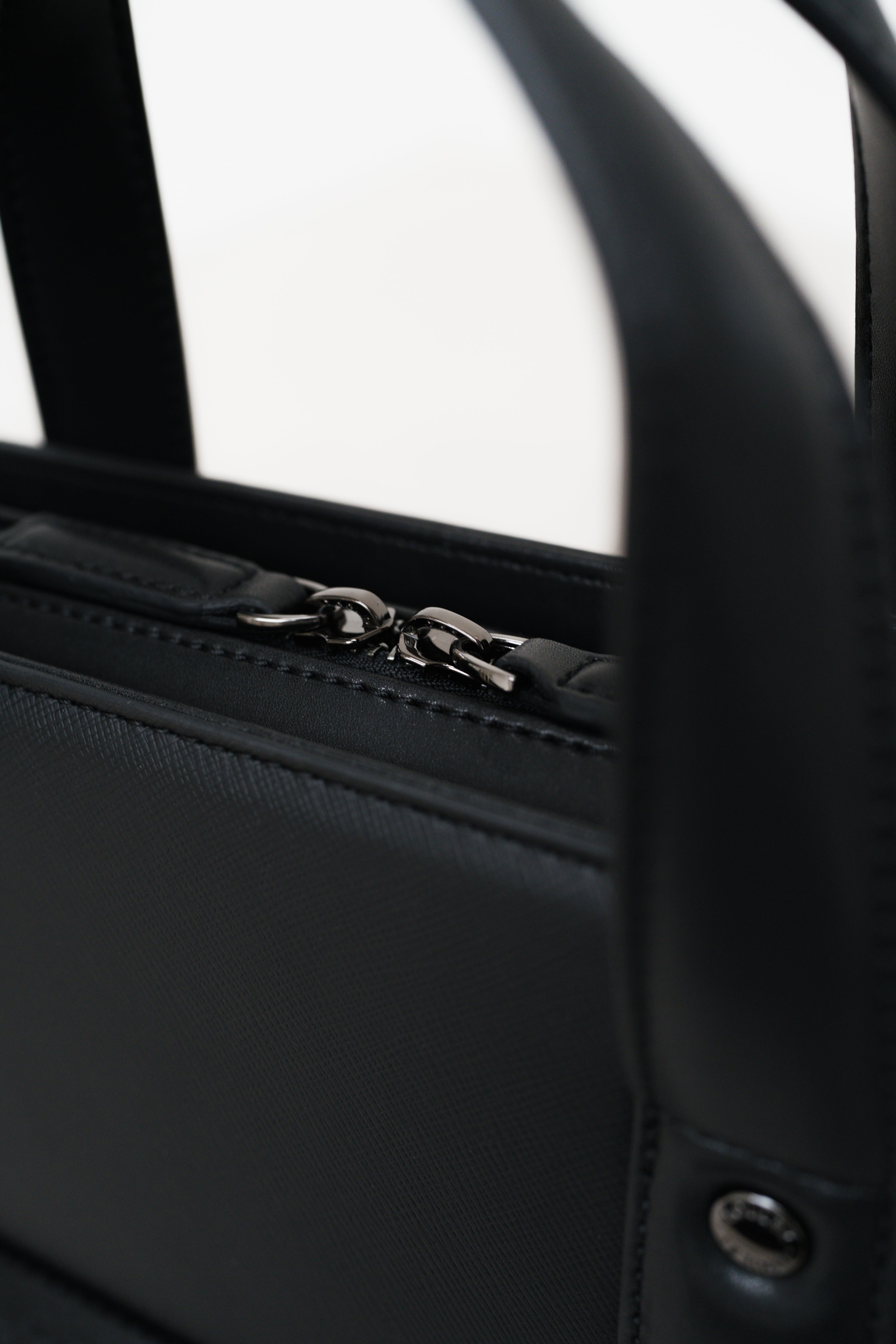 Close-up of a black leather bag with a zipper on a white background